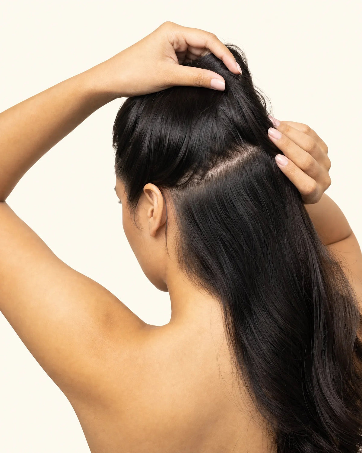 Woman lifting a section of hair to show a healthy scalp parting